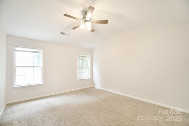 spare room with lofted ceiling, light carpet, visible vents, and baseboards