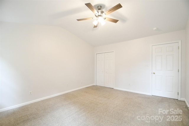 unfurnished bedroom featuring ceiling fan, carpet floors, baseboards, vaulted ceiling, and a closet