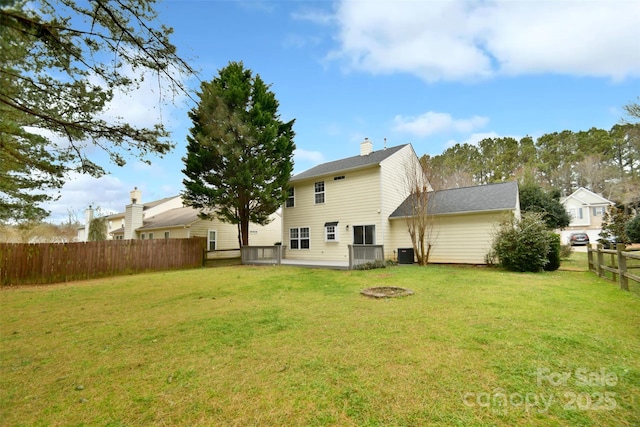 rear view of property with a chimney, fence, central AC, and a yard