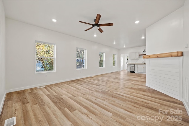 unfurnished living room featuring light hardwood / wood-style flooring, plenty of natural light, and ceiling fan