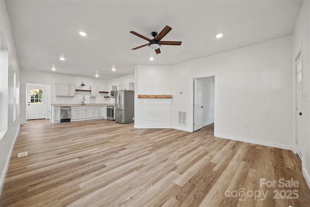 unfurnished living room with ceiling fan, light hardwood / wood-style floors, and sink