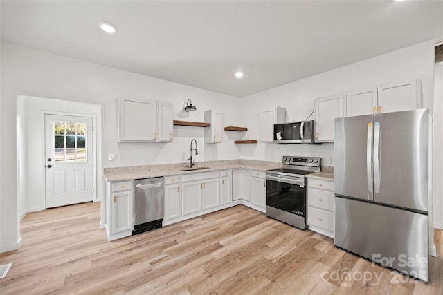 kitchen featuring sink, light hardwood / wood-style flooring, light stone countertops, appliances with stainless steel finishes, and white cabinetry