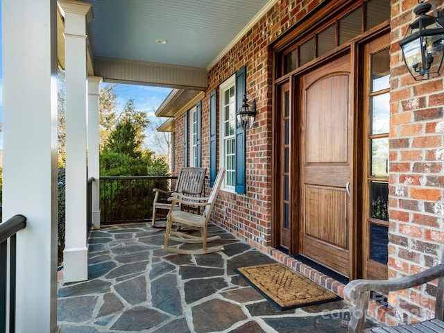 property entrance with covered porch and brick siding