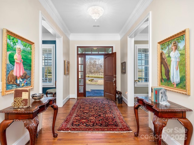 entryway featuring a wealth of natural light, visible vents, crown molding, and wood finished floors