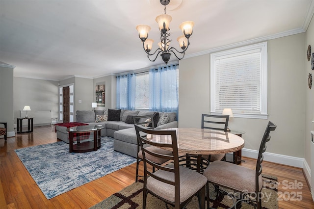 dining area featuring dark hardwood / wood-style flooring, ornamental molding, and an inviting chandelier