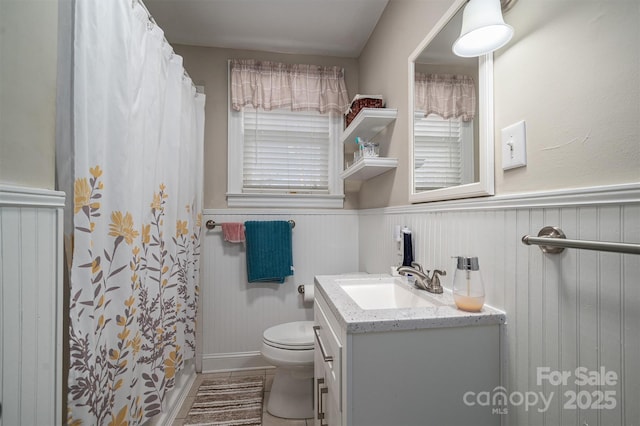 bathroom with a shower with curtain, wooden walls, vanity, and toilet