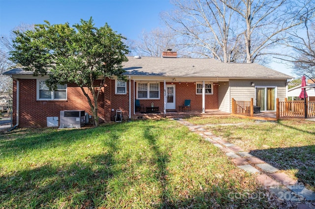 rear view of property with central AC unit and a lawn