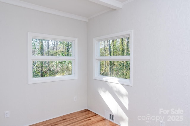 unfurnished room with ornamental molding, plenty of natural light, and wood-type flooring