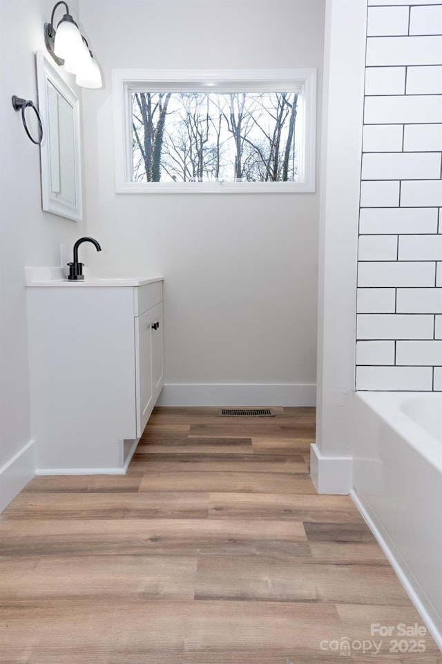 bathroom featuring vanity, hardwood / wood-style floors, a washtub, and a wealth of natural light