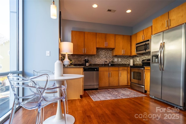 kitchen featuring appliances with stainless steel finishes, backsplash, sink, decorative light fixtures, and dark hardwood / wood-style floors