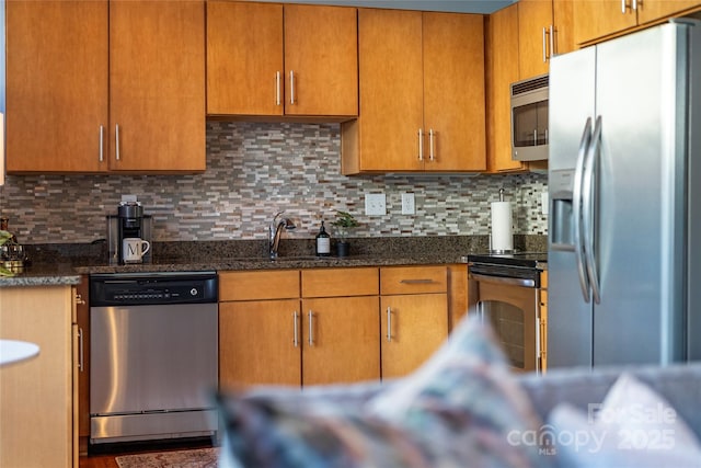 kitchen with backsplash, sink, dark stone counters, and appliances with stainless steel finishes