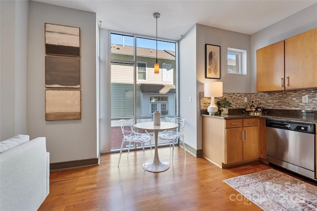 kitchen featuring tasteful backsplash, pendant lighting, dark stone countertops, dishwasher, and light hardwood / wood-style floors