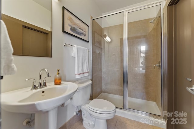 bathroom with tile patterned floors, toilet, a shower with door, and sink