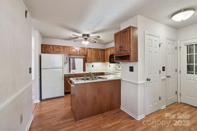 kitchen featuring ceiling fan, sink, kitchen peninsula, white appliances, and light wood-type flooring