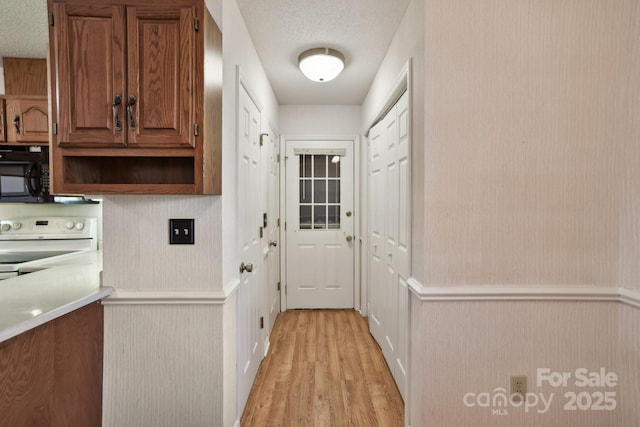 doorway featuring a textured ceiling and light hardwood / wood-style flooring