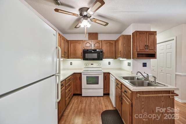 kitchen with white appliances, sink, ceiling fan, light wood-type flooring, and a textured ceiling