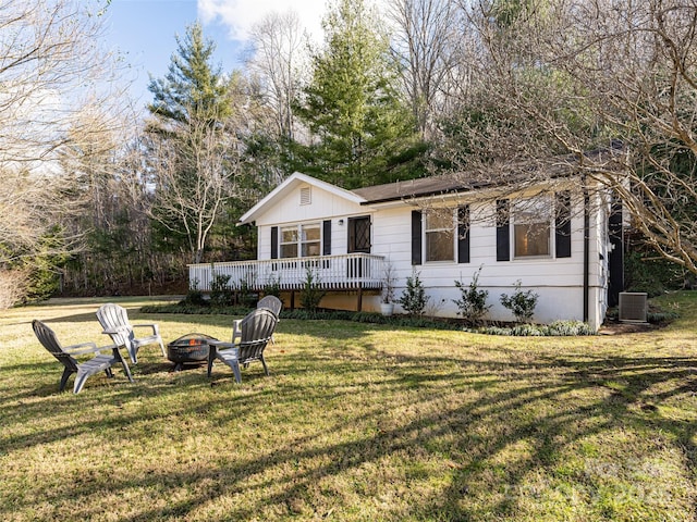 view of front of property featuring a front yard, central AC unit, a fire pit, and a deck