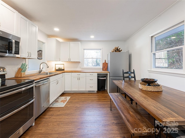 kitchen featuring wood counters, appliances with stainless steel finishes, sink, white cabinets, and dark hardwood / wood-style floors