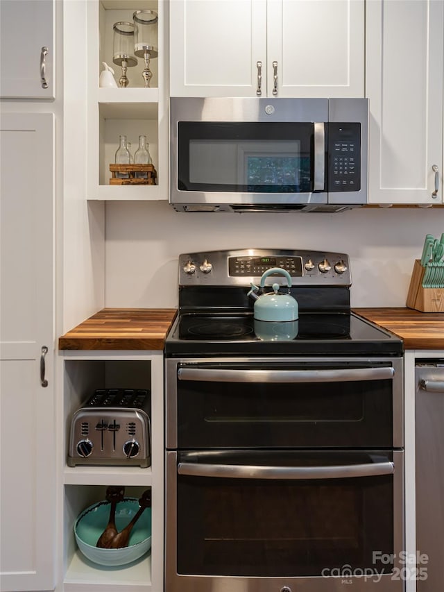 kitchen with white cabinetry, stainless steel appliances, and wooden counters