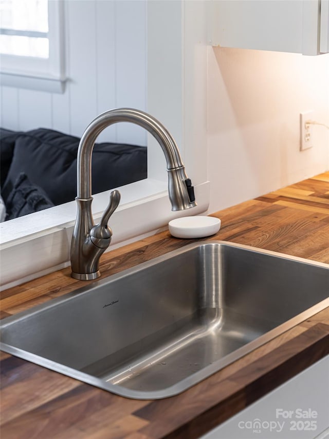 details featuring butcher block counters, sink, and white cabinets