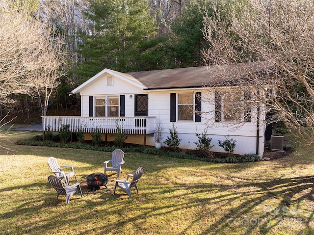 ranch-style home featuring a front yard, central AC, a deck, and an outdoor fire pit