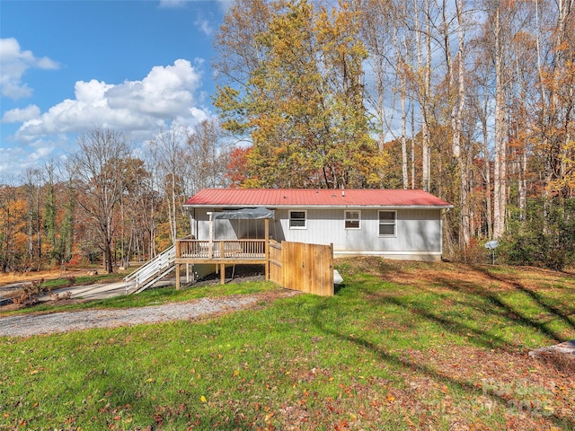 rear view of property featuring a yard and a wooden deck