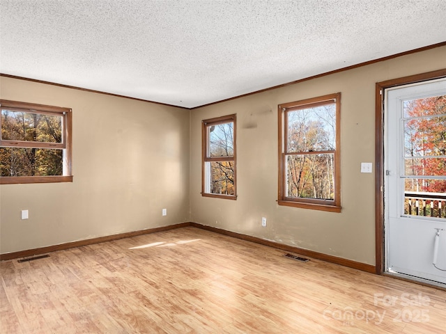 spare room with a textured ceiling, crown molding, and light hardwood / wood-style flooring