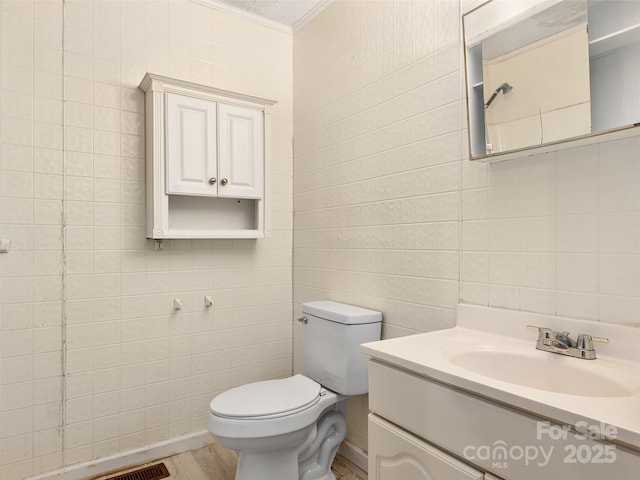 bathroom featuring vanity, toilet, ornamental molding, and tile walls