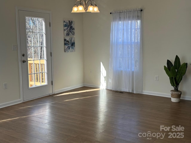 unfurnished room with a chandelier and dark hardwood / wood-style floors