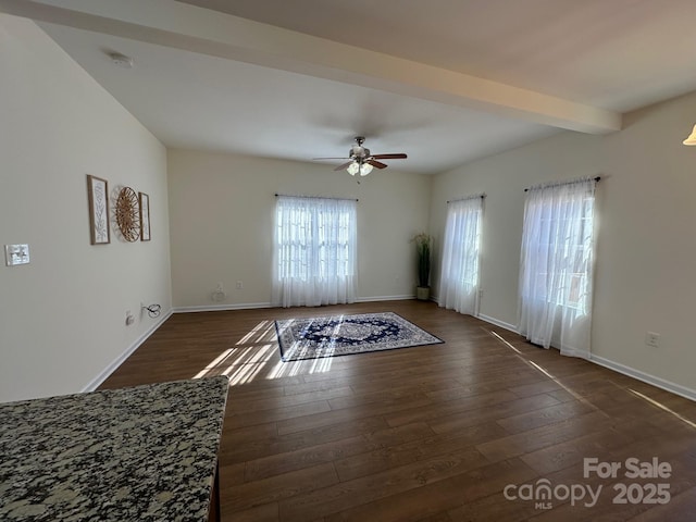 empty room featuring beam ceiling, dark hardwood / wood-style flooring, and ceiling fan