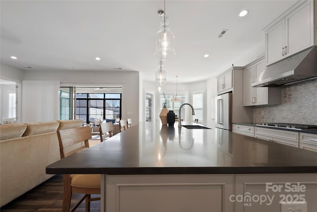 kitchen featuring sink, stainless steel appliances, a spacious island, decorative backsplash, and hanging light fixtures