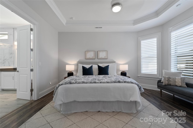 bedroom with ensuite bath, a raised ceiling, ornamental molding, and hardwood / wood-style flooring