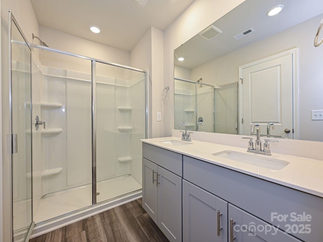 bathroom with hardwood / wood-style floors, vanity, and a shower with door