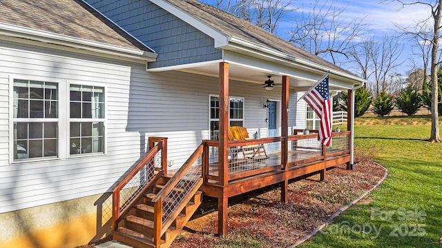 entrance to property featuring a deck, ceiling fan, and a lawn