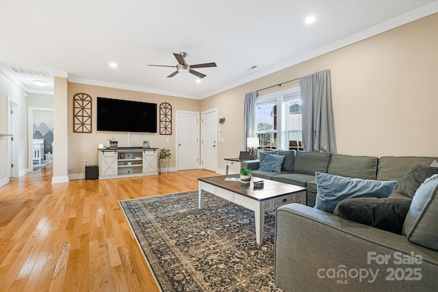 living room with hardwood / wood-style flooring, ceiling fan, and crown molding