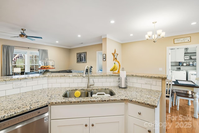 kitchen with dishwasher, white cabinets, ceiling fan with notable chandelier, sink, and washer and dryer