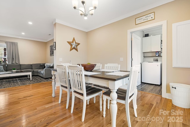 dining area with a notable chandelier, light hardwood / wood-style floors, washer / dryer, and crown molding