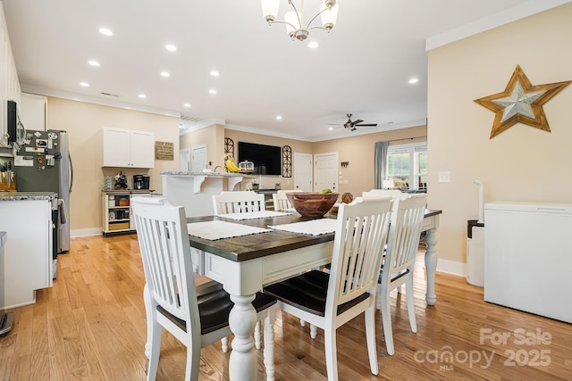 dining room featuring light wood-type flooring, ceiling fan with notable chandelier, and ornamental molding