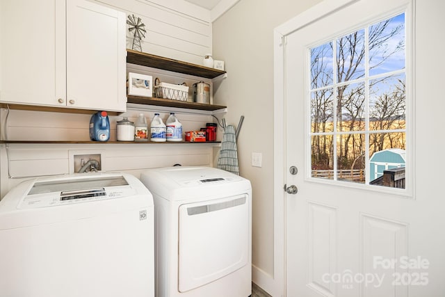 clothes washing area with washer and clothes dryer and cabinets