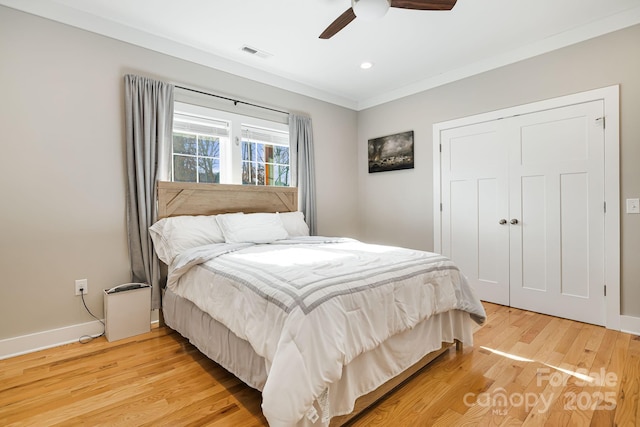 bedroom featuring hardwood / wood-style floors, ceiling fan, ornamental molding, and a closet