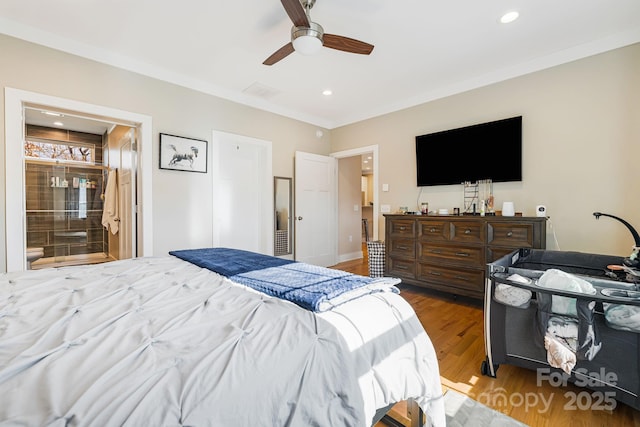 bedroom featuring connected bathroom, light hardwood / wood-style flooring, ceiling fan, and crown molding