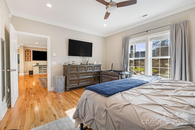 bedroom featuring ceiling fan, crown molding, and light hardwood / wood-style floors