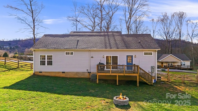 rear view of property featuring a lawn, an outdoor fire pit, a wooden deck, and central AC