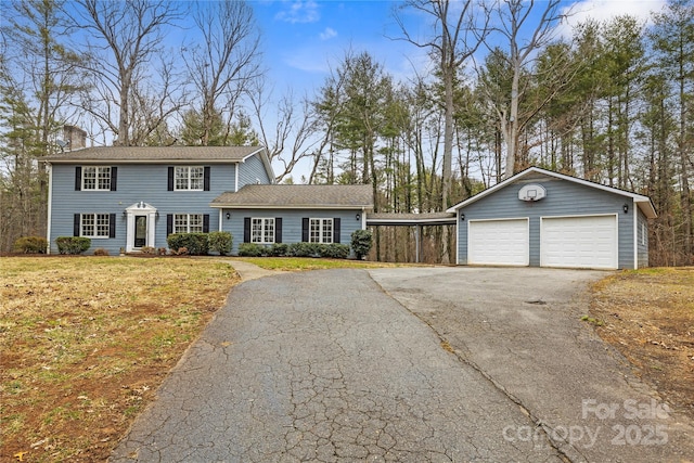 view of front of property featuring a garage, an outbuilding, a front yard, and a chimney