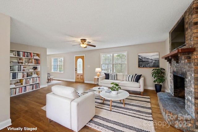 living room with a brick fireplace, wood finished floors, and a wealth of natural light