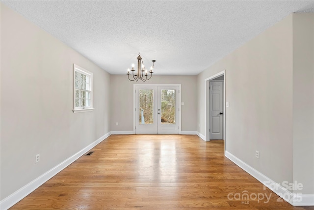 unfurnished dining area with an inviting chandelier, visible vents, light wood-type flooring, and a wealth of natural light