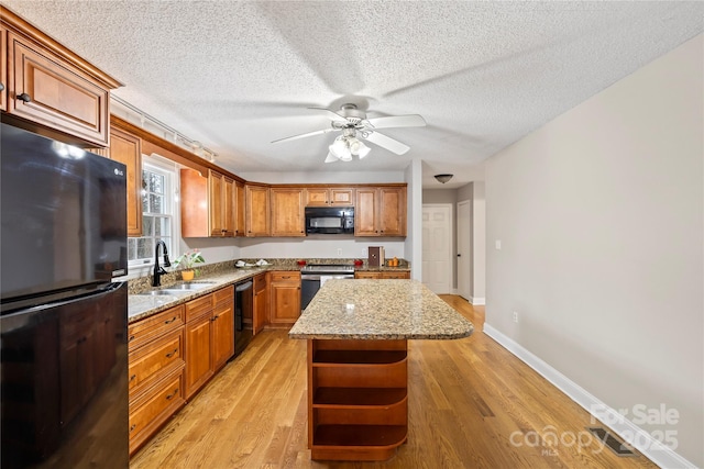 kitchen featuring light wood-type flooring, black appliances, a sink, open shelves, and a kitchen island