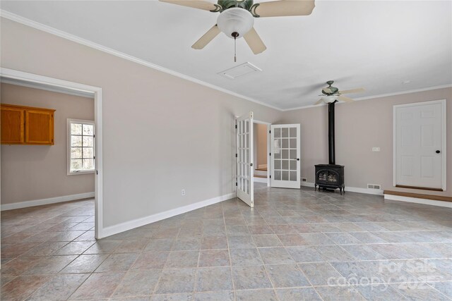 unfurnished living room featuring crown molding, a wood stove, french doors, and visible vents