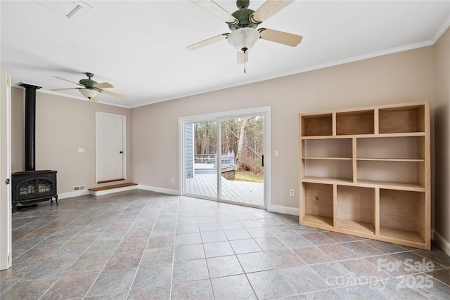 unfurnished living room featuring a wood stove, baseboards, visible vents, and ornamental molding