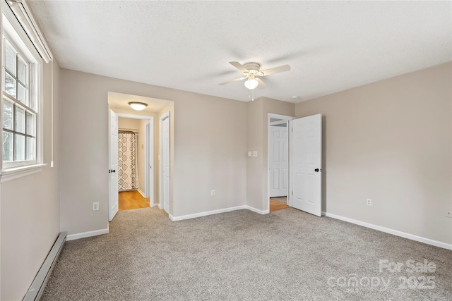 unfurnished bedroom with a baseboard heating unit, baseboards, carpet flooring, a textured ceiling, and a ceiling fan